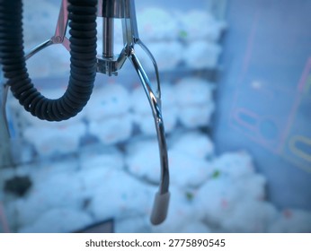Claw Machine Close Up Focus on Metal Claw with Blurred Stuffed Toy Prizes Background. Close-up view of Mechanical Claw Machine Game.