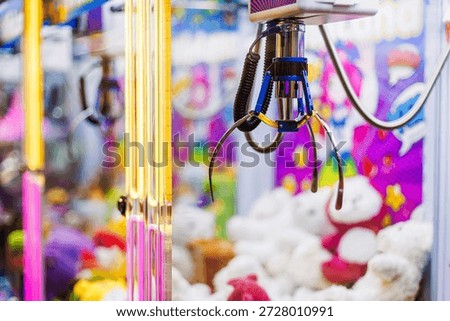 Claw machine inside arcade game center with neon lights and plush toys. Colorful amusement attraction, entertainment concept, modern leisure background with shallow depth of field and copy space.