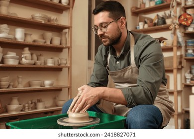 Clay crafting. Man making bowl on potter's wheel in workshop, space for text - Powered by Shutterstock