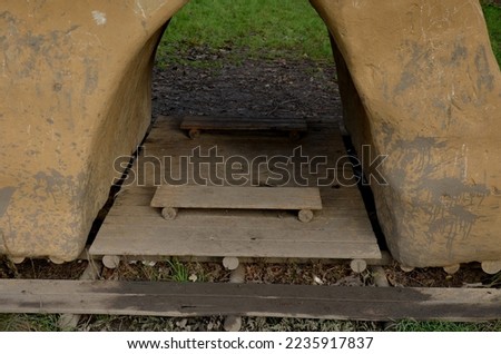 clay experimental house. the frame is made of straw and is painted with a trowel made of natural clay plaster. it resembles a Neolithic dwelling from prehistoric times. wooden floor arch ceiling lawn