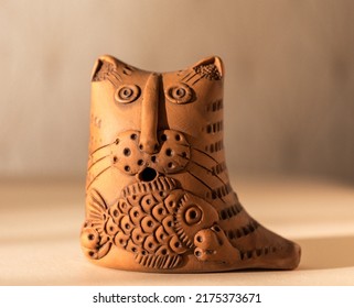 Clay figurine of a cat with a fish on a light background close-up. Crafts made of clay. A cat holds a fish in its paws. Chocolate figurines. Chocolate dessert close-up.