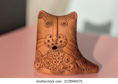 Clay figurine of a cat with a fish on a multicolored background close-up. Handmade clay crafts. A cat holds a fish in its paws. Chocolate figurines. Chocolate dessert close-up.