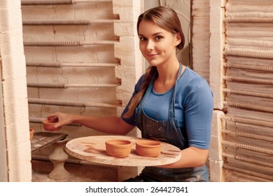 Clay jars created. Young smiling girl puts clay pots to the shelf so that they could get dry - Powered by Shutterstock