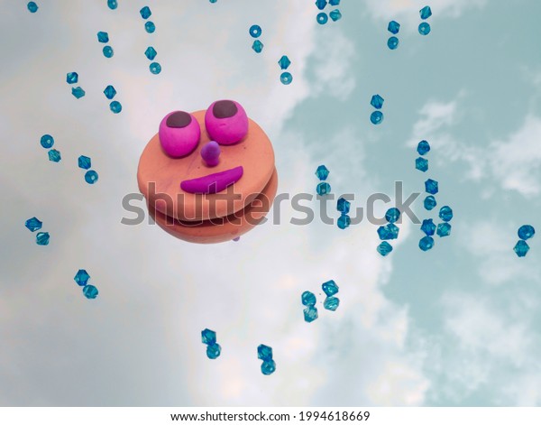 Clay made moon cartoon eyes with smiling face\
and blue crystal\
background