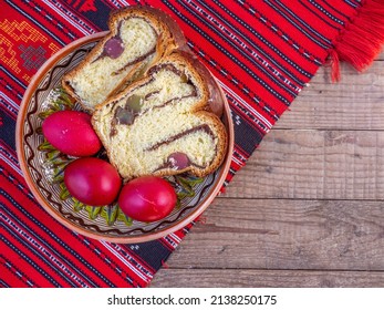 Tonplatte mit Scheiben von traditionellem Osterbrot oder Cozonac- und roten Eiern, romanische Ostertradition