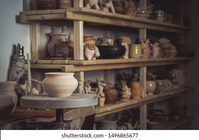 Clay pot close-up on potter's wheel. Inside interior. Wooden racks in pottery workshop in which there are pottery, many different pottery standing on the shelves in a potery workshop. Master crock. - Shutterstock ID 1496865677