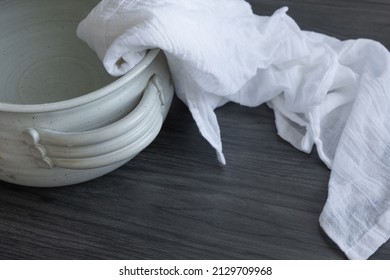 Clay pot of water with white linen cloth on a dark wood background with copy space