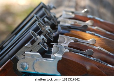 clay shooting guns over a fence, in a safe position. shiny metal and wood handles,  Double Barrelled,