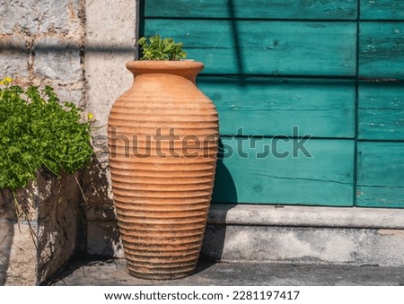Clay terracotta pot amphora standing against the wall of a medieval house in a mediterranean resort