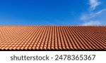 Clay tile roof. Banner with orange clay tile roof close-up on blue sky background with space for text, copy space.