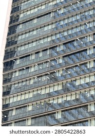 Clean architectural grid pattern formed by repetitive square glass windows on a tall modern city skyscraper tower.