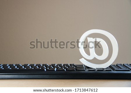 clean at-symbol, at-sign on keyboard with wood surface and negative space, symbol for mail, internet, websites and communication