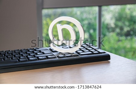 clean at-symbol, at-sign on keyboard with wood surface, symbol for mail, internet, websites and communication, with trees and nature in background