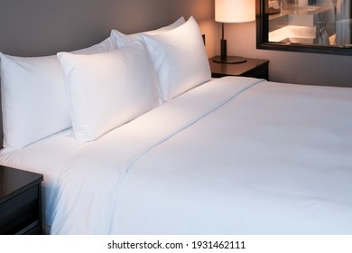 Clean Bedding Sheets And Pillow On Natural Wall Room Background. White Bedding And Pillow In Hotel Room. White Pillows On Empty Bed.