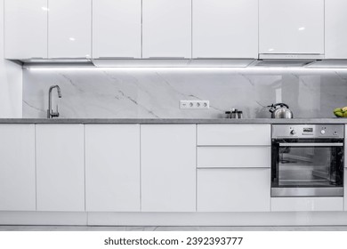 A clean, bright kitchen featuring all-white cabinets and a modern design. Overall ambiance of the kitchen is simplistic, refreshing, and inviting, making it appear very elegant and sophisticated.