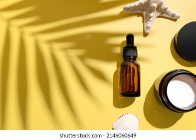 Clean brown glass cosmetic bottles with pipette jar of cream starfish sun shade from tropical leaf on yellow background. Summer concept of natural cosmetics. Spa products for health, beauty. Serum 