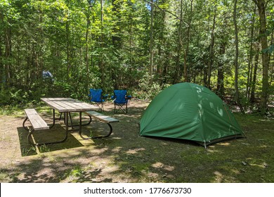 Clean Campsite With Green Tent, Picnic Table And Foldable Camping Chairs In Front Of The Fire Pit. Camping, Hiking, Vacation Concept. Northern Ontario, Canada.
