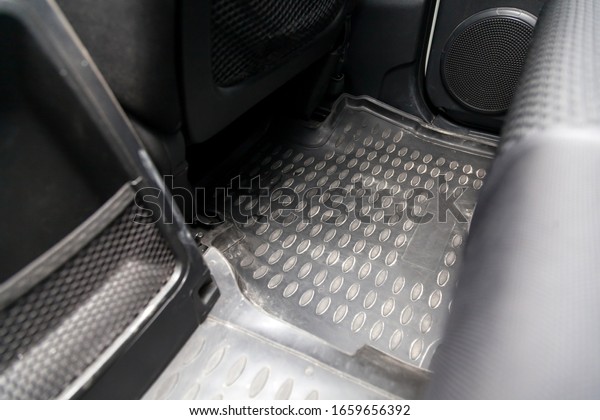Clean car floor mats\
of black rubber under rear passenger seat in the workshop for the\
detailing vehicle before dry cleaning. Auto service industry.\
Interior of sedan.