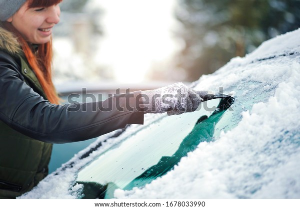 Clean car window from snow in\
winter time. Windshield cars cleaning. Removing snow from\
windows.