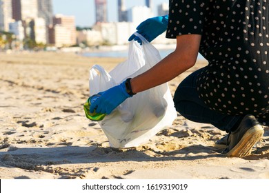 Clean City Beach From Trash. Woman Hand Picking Up Empty Soft Drinks Cans Trash And Plastic Bottles From The Beach