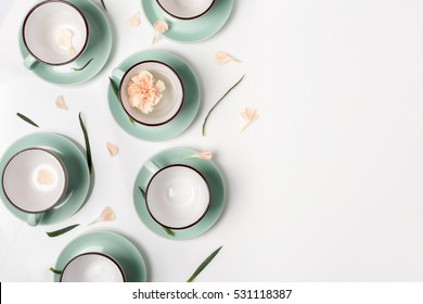 Clean Dishes, Coffee Or Tea Set. Composition Of Elegant Porcelain Cups And Saucers With Flower Petals And Copy Space At White Background, High Key, Top View And Flat Lay.