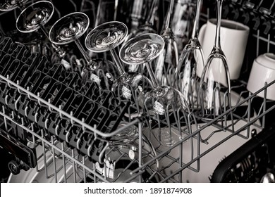 Clean Dishes In The Dishwasher. Wine Glasses, Sparkling Wine Glasses, White Cups. Close-up. Washing-up And Housework Concept