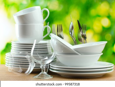 Clean Dishes On Wooden Table On Green Background