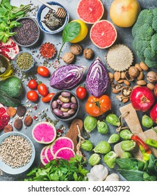 Clean eating concept over grey concrete background, top view. Vegetables, fruit, seeds, cereals, beans, spices, superfoods, herbs for vegan, gluten free, allergy-friendly weight loosing or raw diet