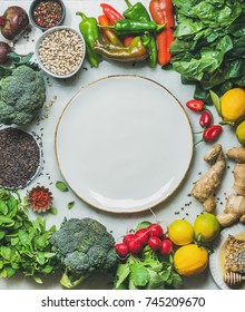 Clean Eating Healthy Cooking Ingredients. Vegetables, Beans, Grains, Greens, Fruit, Spices Over Grey Marble Background, White Plate With Copy Space In Center, Top View. Diet Food Concept. Food Frame