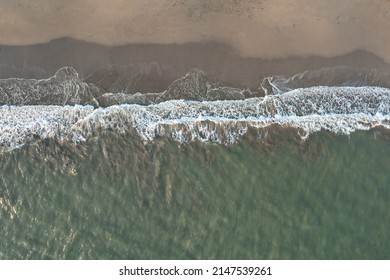 Clean empty beach with waves above drone top view