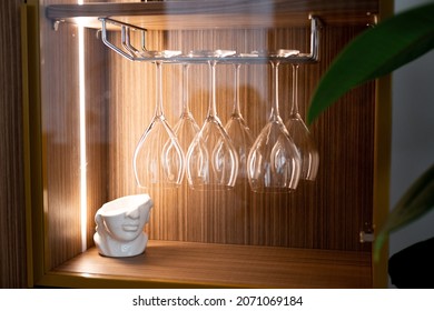 Clean Empty Overturned Wine Glasses In Illuminated Wooden Display Cabinet In Modern Interior. Soft Selective Focus, Art Noise