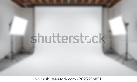 A clean and empty photography studio set up with a large white backdrop and two professional softbox lights on stands, ready for a photoshoot.