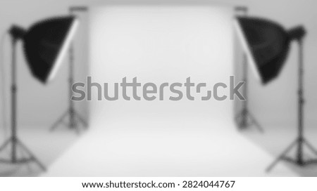 A clean and empty photography studio with two professional softbox lights on stands illuminating a seamless white background, ready for a photoshoot.