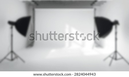 A clean and empty photography studio with two professional softbox lights on stands illuminating a seamless white backdrop, ready for a photoshoot.