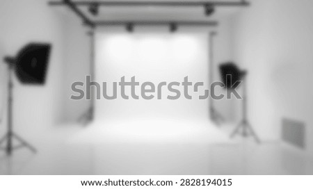 A clean and empty professional photography studio setup with softbox lights and a white backdrop ready for a photoshoot.