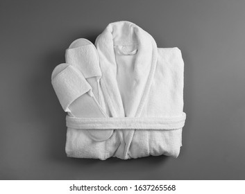 Clean folded bathrobe and slippers on grey background, top view