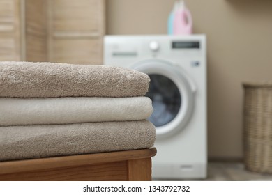 Clean folded towels on table in modern laundry room, space for text