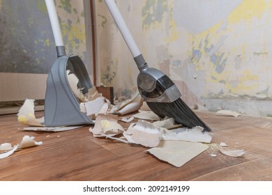 Clean up garbage after repairs.Sweep up construction debris with a brush in a dustpan.Sweeping at home.Tools for cleaning the house.Make home repairs.The dust.Wall repair.Torn wallpaper from the wall - Shutterstock ID 2092149199