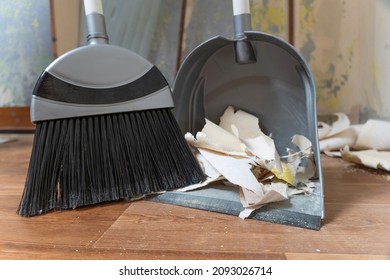 Clean Up Garbage After Repairs.Sweep Up Construction Debris With A Brush In A Dustpan.Sweeping At Home.Tools For Cleaning The House.Make Home Repairs.The Dust.Wall Repair.Torn Wallpaper From The Wall