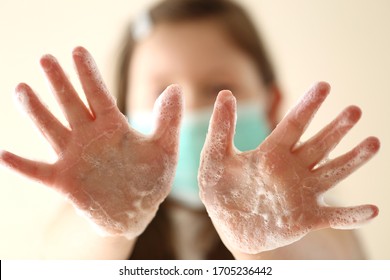 Clean Hands Concept. Hand Washing.Coronavirus Epidemic.Girl Child In A Medical Protective Mask Shows Hands In Soap Foam Close-up. Hygiene And Health .Precautions For Viral Diseases.