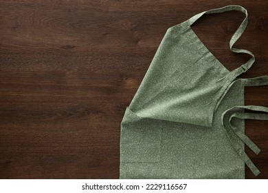 Clean kitchen apron with pattern on wooden table, top view. Space for text