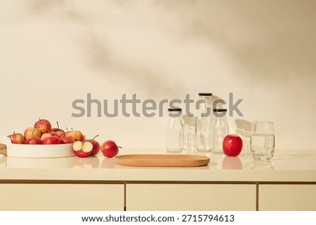 A clean kitchen set with apples, jars and wooden plate. Neutral tones, natural shadow leave, fruit stand out. Organic fruit with kitchen background, space for product display