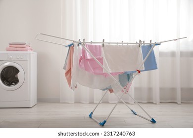 Clean laundry hanging on drying rack indoors