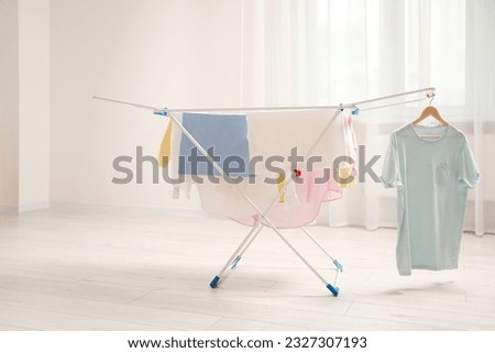 Clean laundry hanging on drying rack indoors