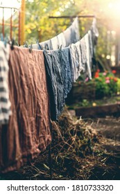 Clean Laundry Linen Clothes Hanging On Washing Line And Drying By Sunshine In Fresh Air In Garden Outdoor. Solar Energy. Yard Landscape Background. Clothespin On Rope. Ecological Way To Do Housework.