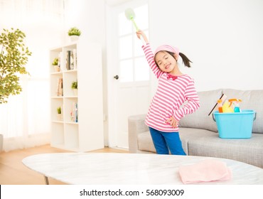 Clean Little Girl Having Fun During Spring Cleaning. Funny Kids Cleaning Wearing Pink Top Singing Into Broom. Housework And Household Concept.