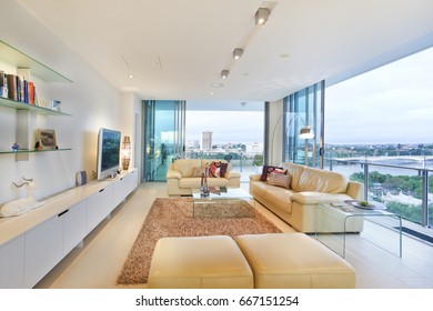 Clean Living Area With Television, Comfortable Furniture And Designs, Walls Are White Color, Chairs Around The Tables, Inside Rooms Of A Apartment.
