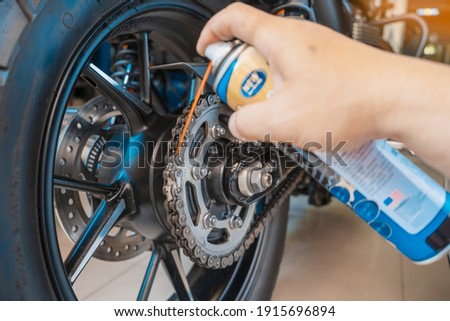 clean and lube a motorcycle chain with oil Spray in Motorcycle garage, service and maintenance concept