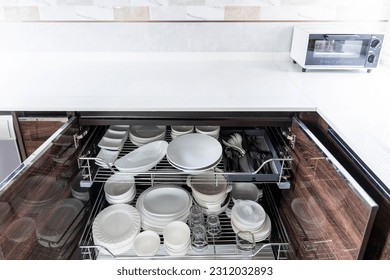 The clean luxury modern design of kitchen with wooden cabinets.Dish shelf with white table top.Electric dishwasher and oven.Microwave and cooker hood with beautiful shelf.Plant decorate.Copy space. - Shutterstock ID 2312032893