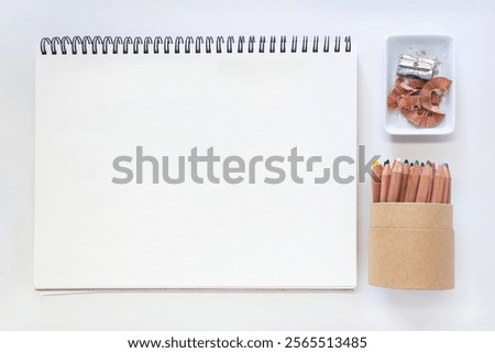 Clean, modern flat lay composition featuring a pristine white sketchbook with spiral binding alongside essential drawing tools.